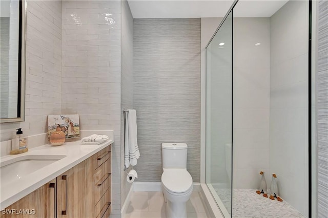 bathroom with tile walls, vanity, walk in shower, toilet, and tile patterned floors