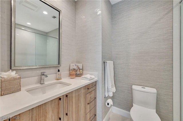 bathroom with vanity, tile walls, and toilet