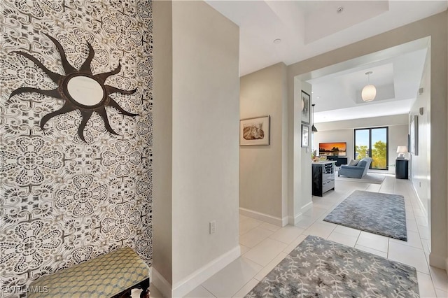 hallway with a raised ceiling and light tile patterned flooring