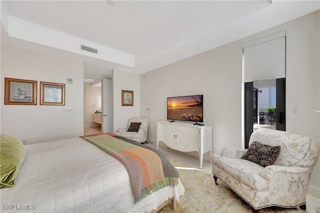 bedroom with ensuite bath and a raised ceiling