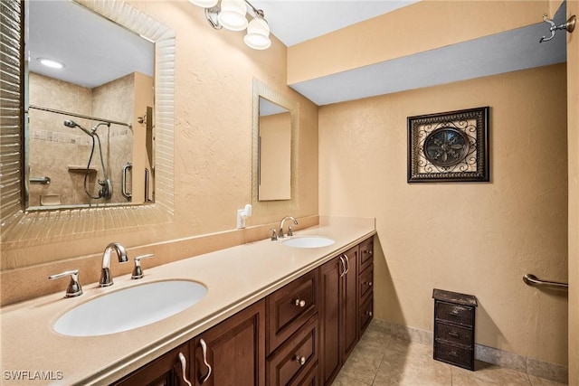 bathroom featuring tiled shower, vanity, and tile patterned flooring