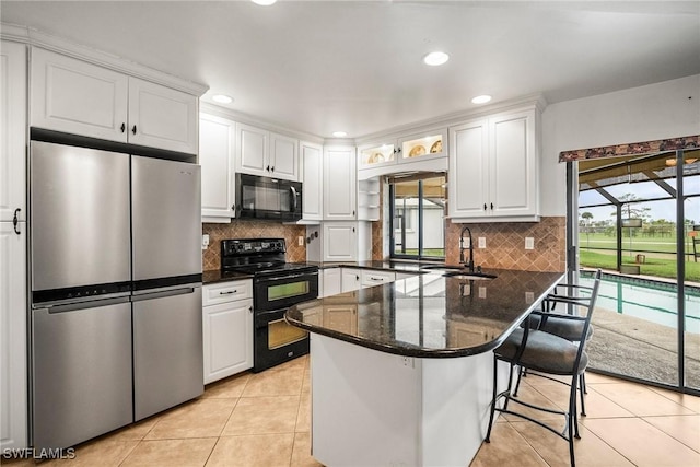 kitchen featuring sink, a breakfast bar, white cabinetry, black appliances, and kitchen peninsula