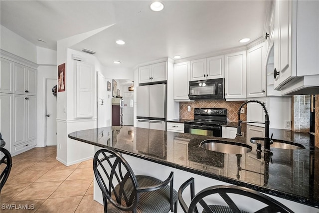 kitchen featuring black appliances, white cabinets, dark stone counters, light tile patterned floors, and kitchen peninsula