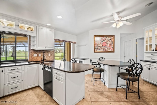 kitchen with backsplash, dishwasher, white cabinets, and a kitchen bar