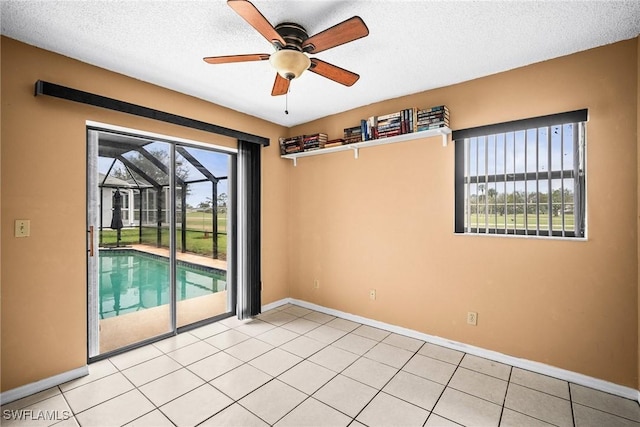 spare room featuring ceiling fan, a textured ceiling, and light tile patterned floors