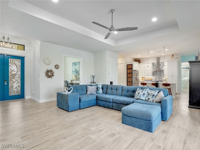 living room featuring a tray ceiling, light hardwood / wood-style floors, and ceiling fan