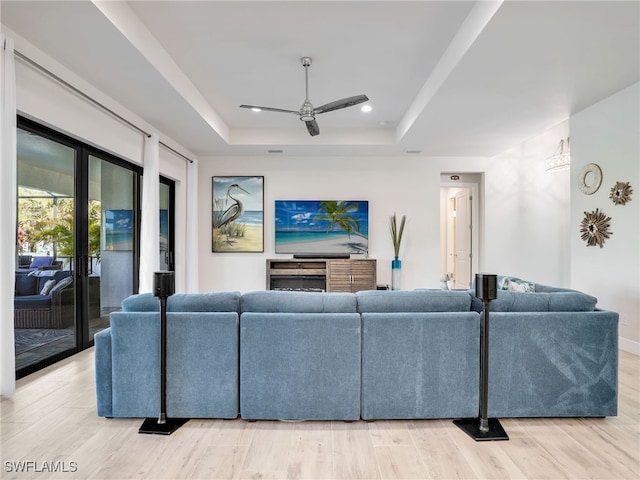 living room with french doors, light wood-type flooring, ceiling fan, and a tray ceiling