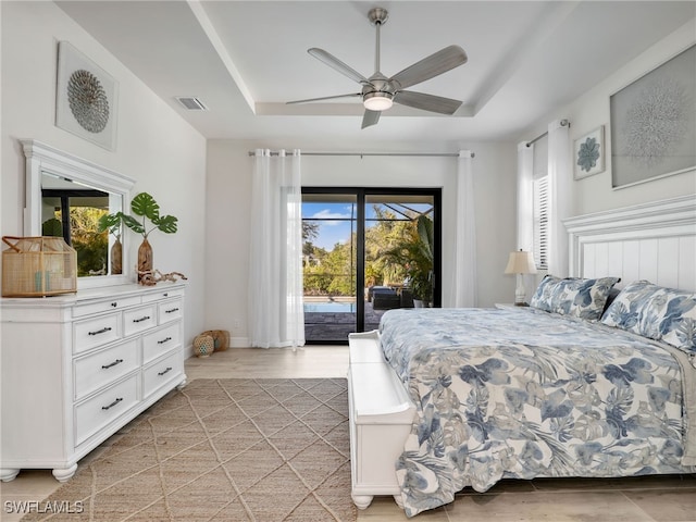 bedroom with a tray ceiling, access to outside, ceiling fan, and light wood-type flooring