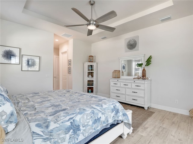 bedroom featuring a raised ceiling, ceiling fan, and light hardwood / wood-style floors