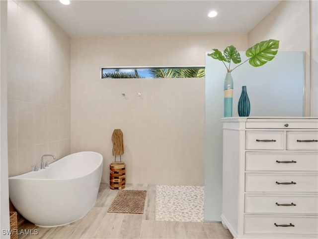 bathroom with a tub and tile walls