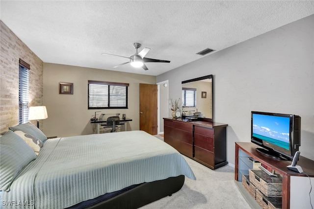 bedroom featuring multiple windows, ceiling fan, light colored carpet, and a textured ceiling