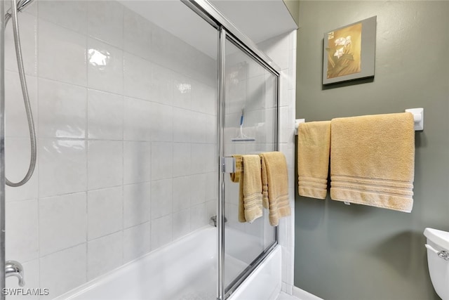 bathroom featuring combined bath / shower with glass door and toilet