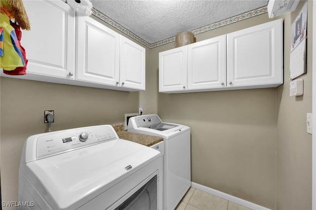 laundry area with cabinets, separate washer and dryer, a textured ceiling, and light tile patterned floors