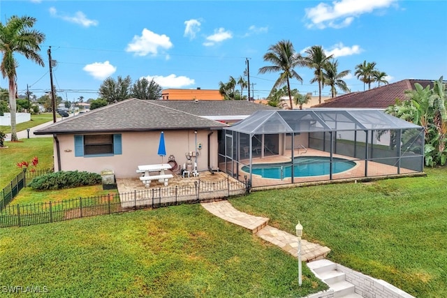 back of property with a fenced in pool, a yard, and glass enclosure