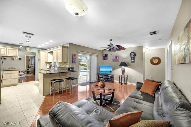 living room featuring ceiling fan, sink, and light tile patterned floors