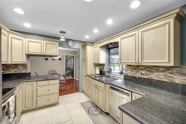 kitchen with sink, light tile patterned floors, backsplash, stainless steel appliances, and dark stone counters