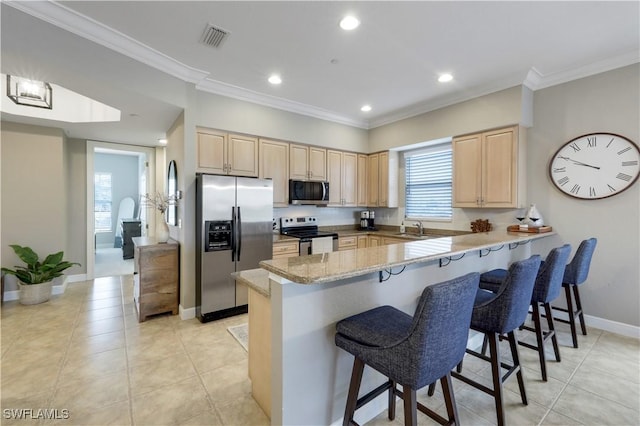 kitchen featuring a breakfast bar, light brown cabinetry, sink, kitchen peninsula, and stainless steel appliances