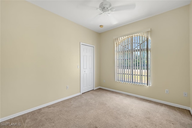 carpeted spare room featuring ceiling fan