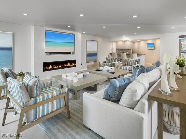 living area with a lit fireplace, visible vents, and recessed lighting