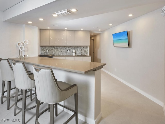 kitchen featuring modern cabinets, a breakfast bar area, a peninsula, backsplash, and recessed lighting