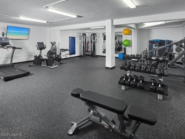 exercise room with a textured ceiling and baseboards