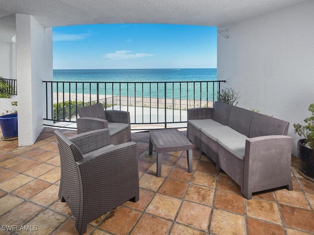 balcony with a view of the beach, an outdoor hangout area, and a water view