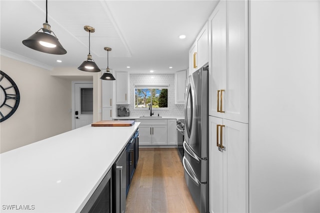 kitchen with sink, white cabinetry, tasteful backsplash, pendant lighting, and stainless steel appliances