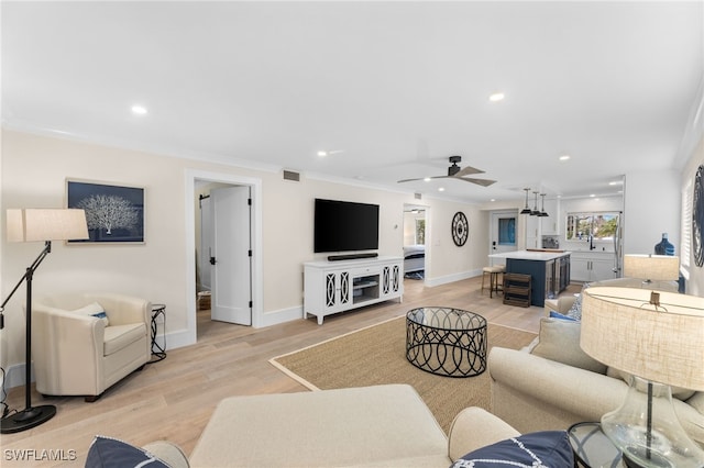 living room featuring ornamental molding, light hardwood / wood-style floors, and ceiling fan