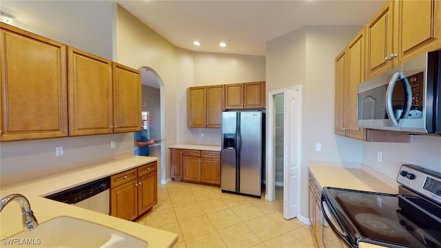 kitchen featuring vaulted ceiling, appliances with stainless steel finishes, sink, and light tile patterned floors