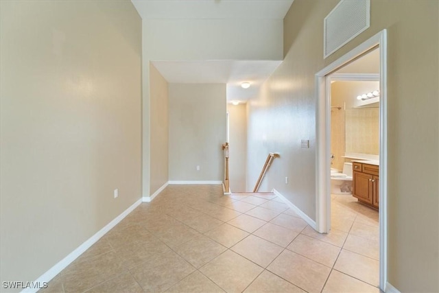 empty room featuring light tile patterned floors, visible vents, and baseboards