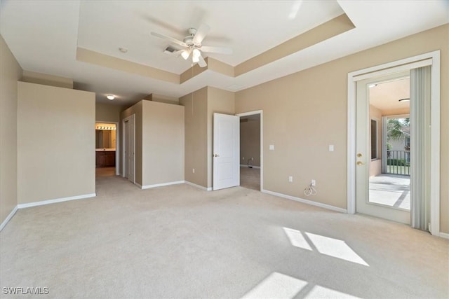 unfurnished bedroom with light carpet, access to outside, and a raised ceiling