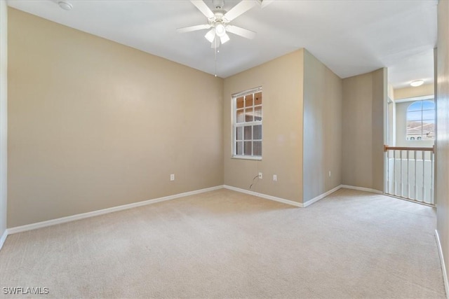 empty room with baseboards, a ceiling fan, and light colored carpet