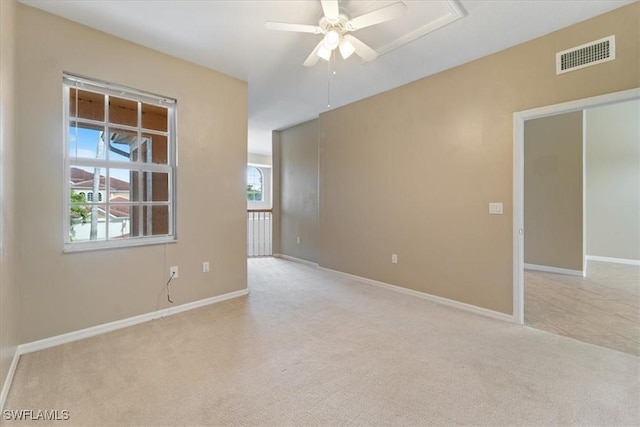 spare room featuring baseboards, ceiling fan, visible vents, and light colored carpet