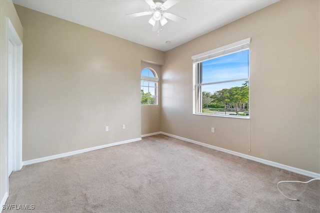 spare room featuring a ceiling fan, light colored carpet, and baseboards