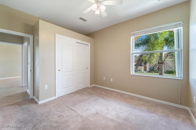 unfurnished bedroom featuring baseboards, a closet, visible vents, and light colored carpet