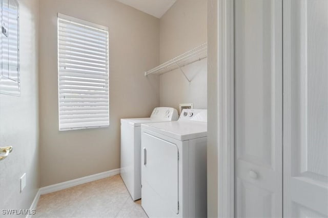 laundry area with laundry area, light tile patterned flooring, baseboards, and washing machine and clothes dryer