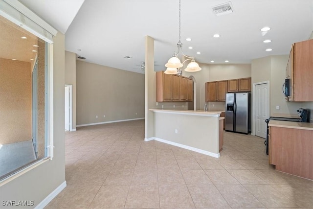 kitchen featuring stainless steel appliances, open floor plan, light countertops, brown cabinetry, and decorative light fixtures