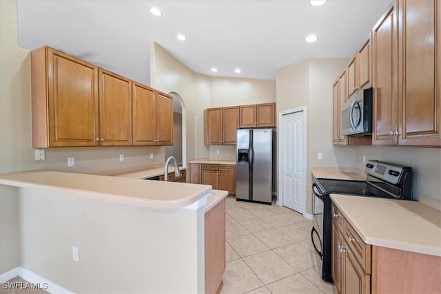 kitchen with stainless steel appliances, brown cabinetry, a peninsula, and light countertops