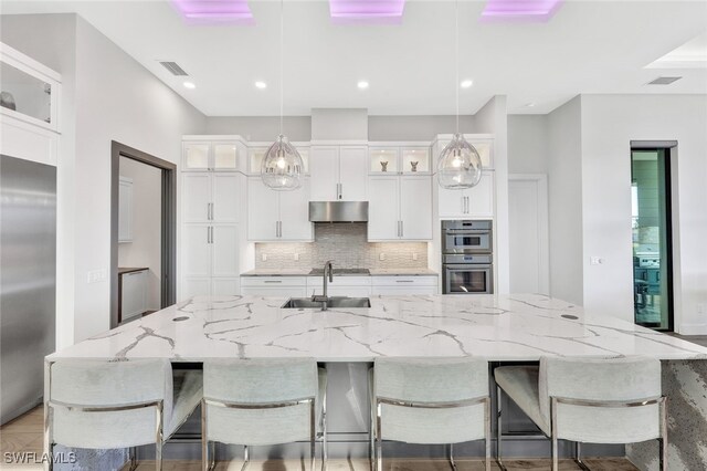 kitchen with sink, white cabinetry, decorative light fixtures, and a large island