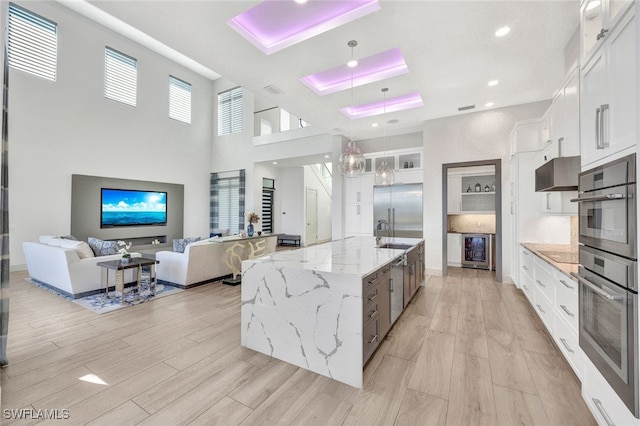 kitchen featuring white cabinets, decorative light fixtures, light stone countertops, and a spacious island