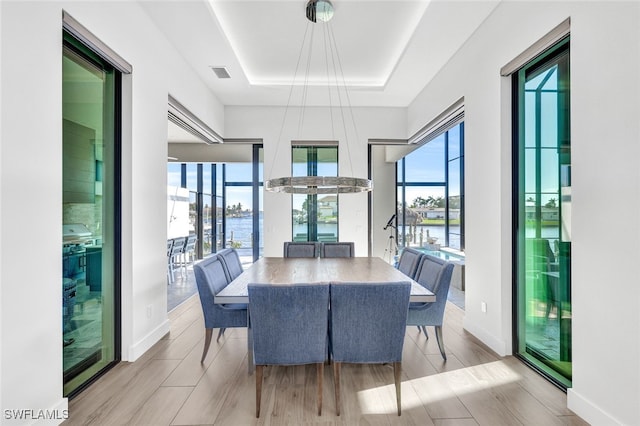 dining area with a water view, a wealth of natural light, and a raised ceiling