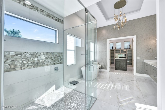 bathroom featuring an inviting chandelier, vanity, a raised ceiling, and plus walk in shower