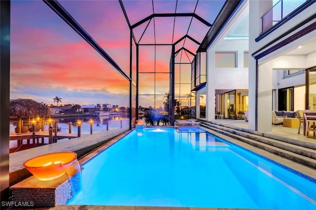 pool at dusk featuring a patio, a water view, glass enclosure, outdoor lounge area, and a hot tub