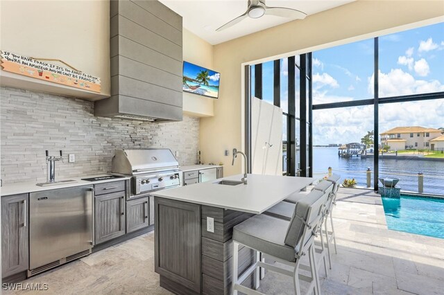 view of patio with exterior kitchen, ceiling fan, an outdoor wet bar, and area for grilling