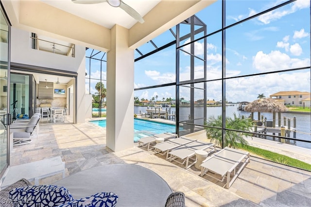 view of pool featuring glass enclosure, a bar, a patio area, a water view, and ceiling fan