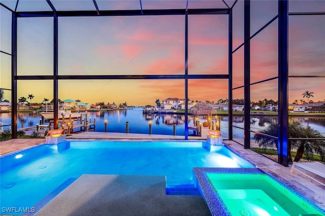 pool at dusk featuring an in ground hot tub, a lanai, a water view, and a boat dock