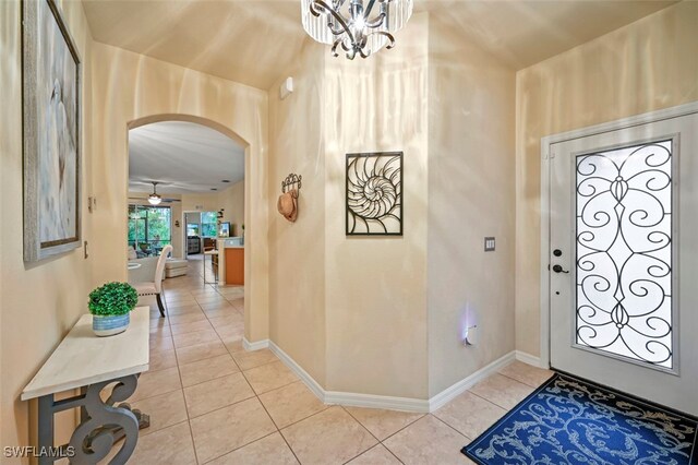 tiled foyer featuring ceiling fan with notable chandelier