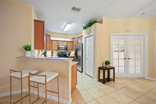 kitchen featuring visible vents, a breakfast bar area, light countertops, appliances with stainless steel finishes, and a peninsula