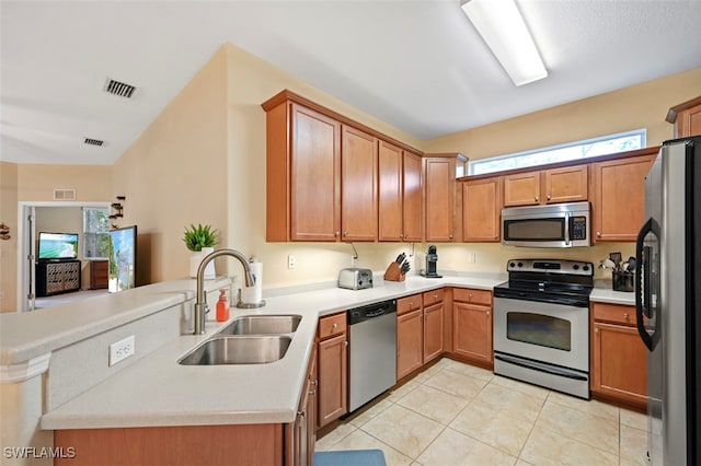 kitchen with visible vents, a peninsula, stainless steel appliances, and a sink