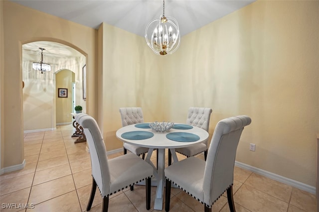 dining area with light tile patterned floors, baseboards, arched walkways, and an inviting chandelier